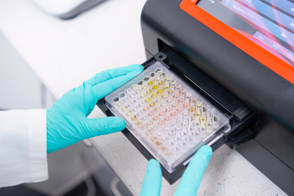 Scientist loading a 96-well plate for qPCR analysis using PCR sealing film to prevent evaporation.